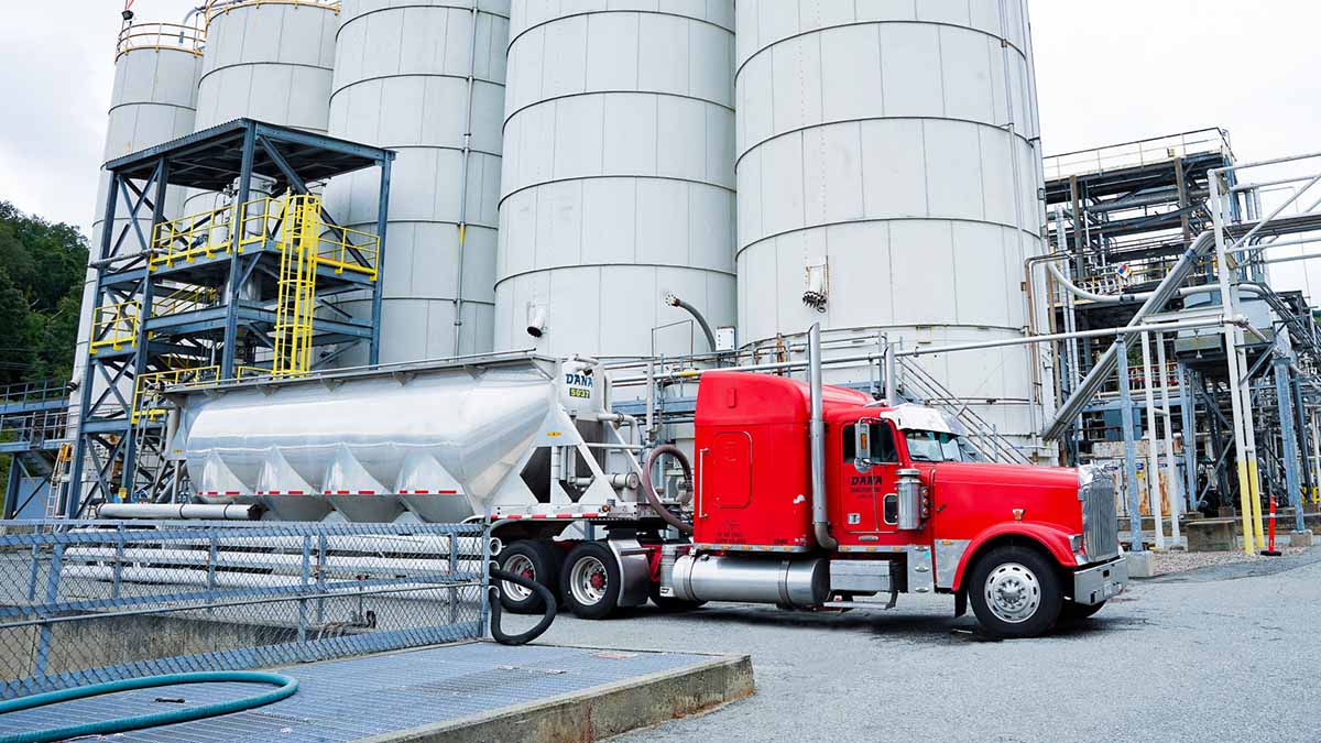 Semi truck parked beside large silos