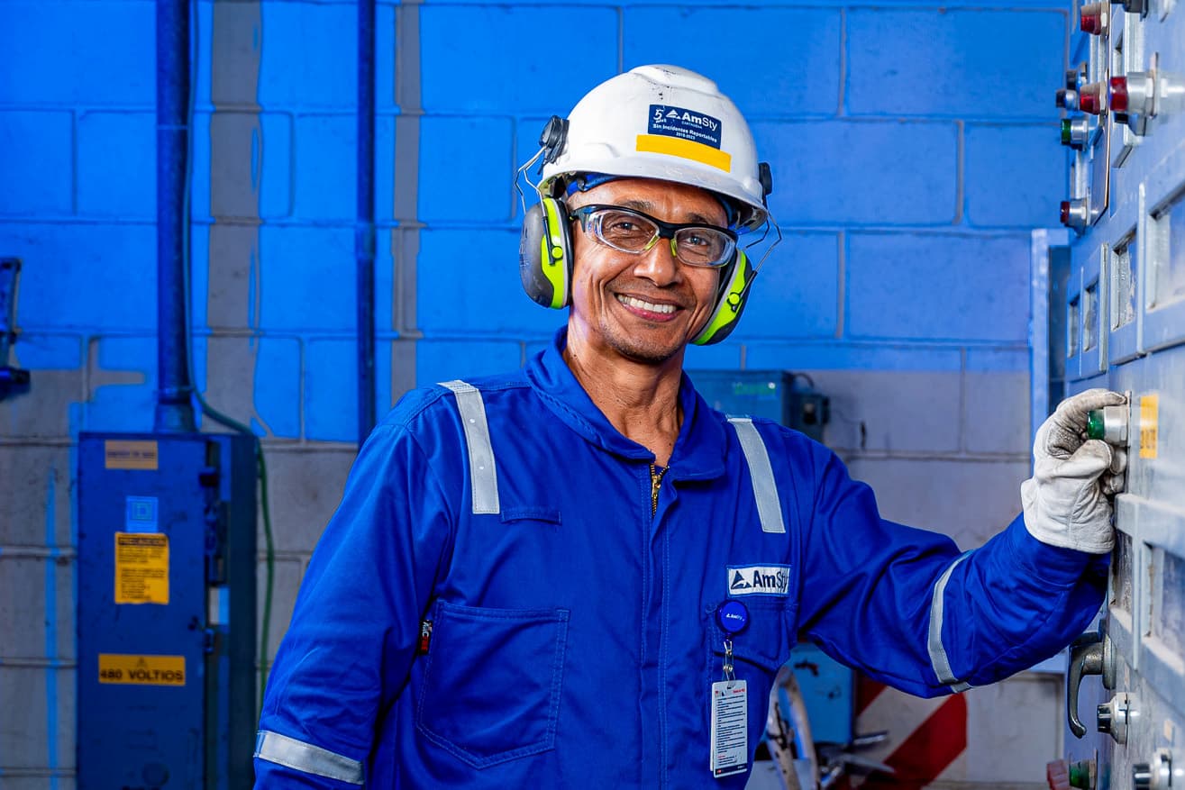 A male employee in personal protective equipment adjusts a dial on a machine