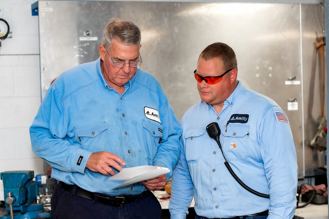 An older employee shows documents to a younger employee