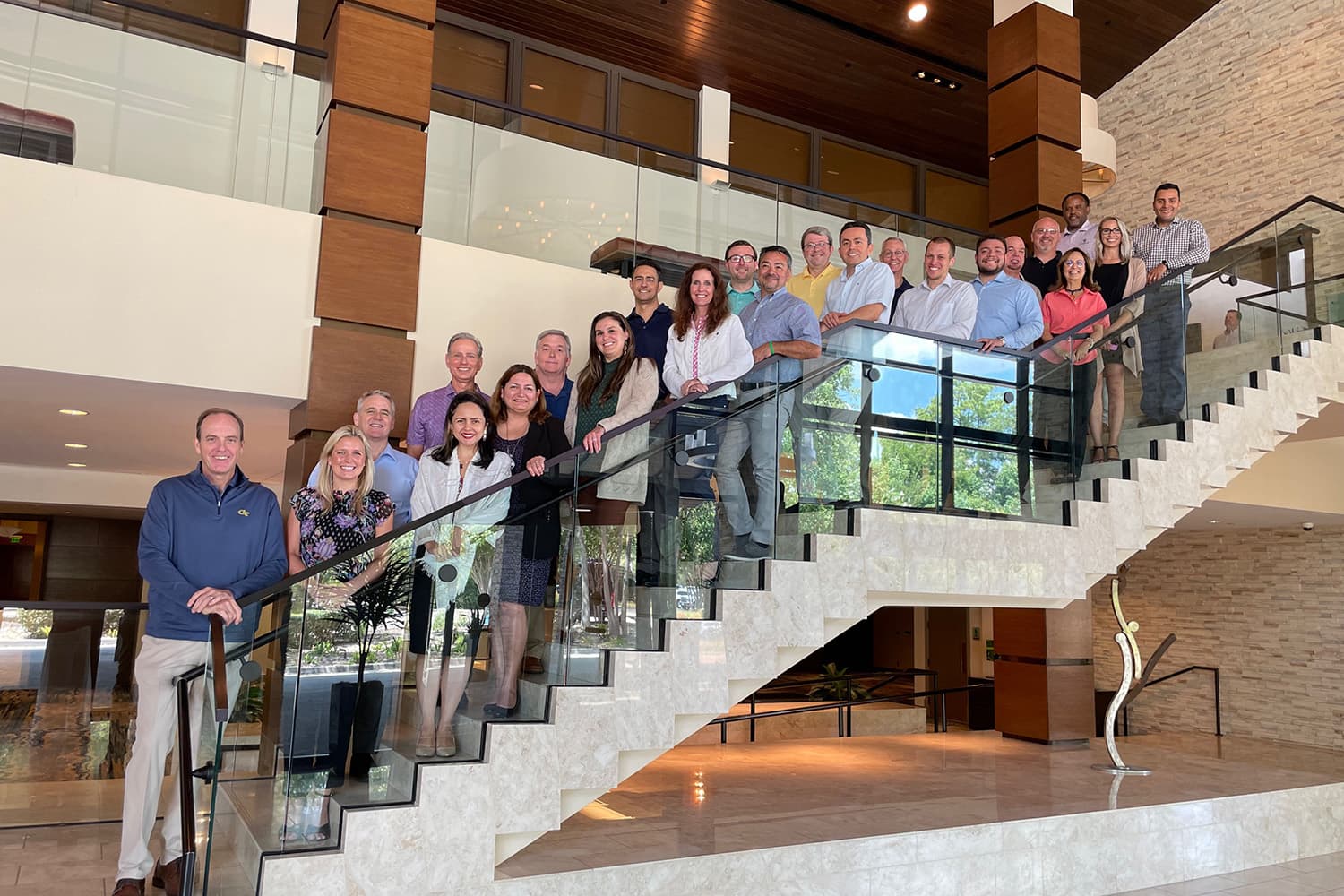 Group of employees in professional dress stand on a stairway in an office lobby