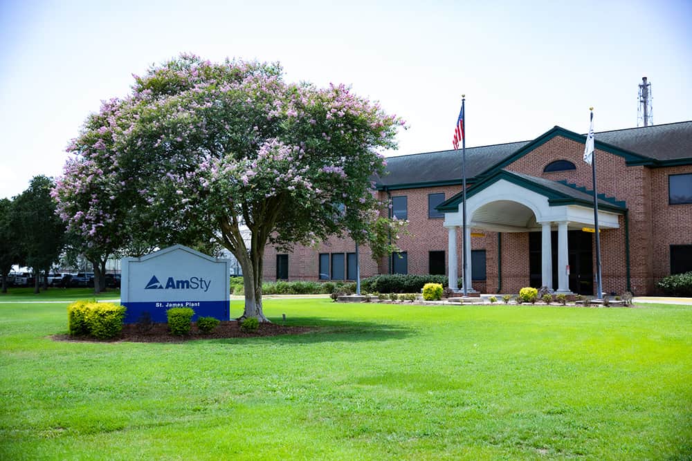 An outside view of an office with a company sign, American flag on a pole and a tree blooming