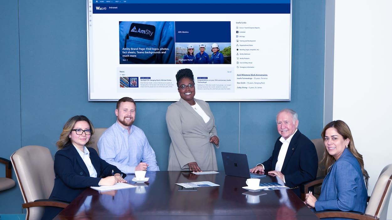 Woman stands in front of screen with employees seated at table